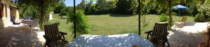 Blick von der schattigen Terrasse unter der Pergola in den Garten (Panorama-Aufnahme)